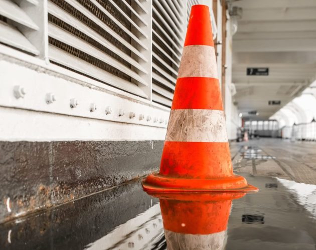 selective-shot-orange-traffic-cone-side-hallway-with-puddle-reflecting-it-min